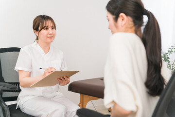 腹痛で悩む女性を診察する医師・整体師（整体・整骨）
