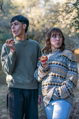 Fototapeta premium two friends walking at dusk in the forest eating apples