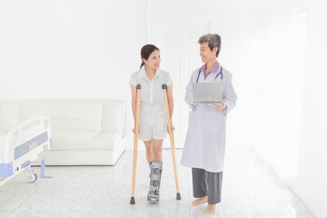 asian patient learning to use crutches with doctor, she wear air cast walking bootwalk, training and rehabilitation, doctor assessment of patient leg