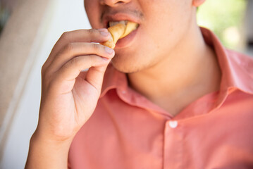 A young man is eating and enjoy his food.