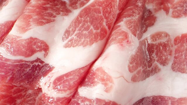 The pork neck slice. The pink color is indicative of the meat's freshness, while the white areas represent the presence of fat, which contributes to the meat's tenderness and flavor. Meat concept. 4K
