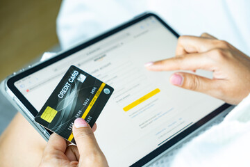 Woman holding credit card and he is shopping online on tablet and using credit card to pay bills concept of finance and banking	
