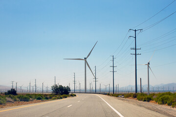 California highway, view of wind turbine, electrical poles and electrical wires. Clean and...