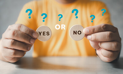 Man holding two wooden blocks with yes or no written on them, making the decision concept. Yes or...