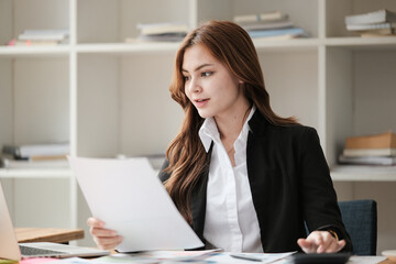 Asian Business woman using calculator and laptop for doing math finance on an office desk, tax, report, accounting, statistics, and analytical research concept 