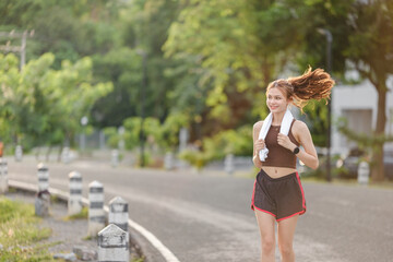 Fototapeta premium Healthy Asian woman is jogging running outdoor. Sport girl running. Female exercising at outdoor park. Sunset or Sunrise.