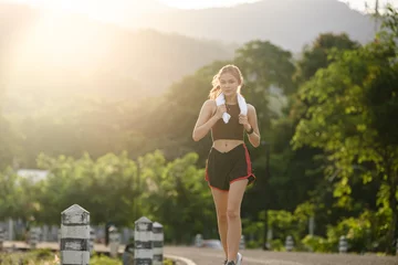 Keuken spatwand met foto Healthy Asian woman is jogging running outdoor. Sport girl running. Female exercising at outdoor park. Sunset or Sunrise. © Treerat