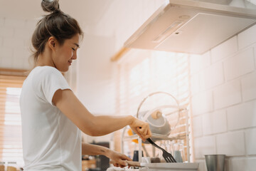 Asian woman in white t-shirt cooking in the kitchen making lunch.