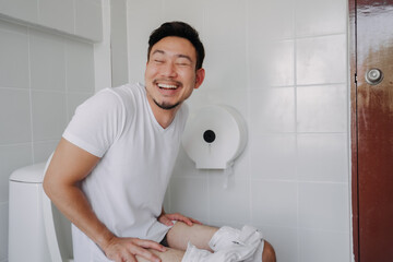 Funny happy face of asian man able to poop after suffer from constipation. - obrazy, fototapety, plakaty