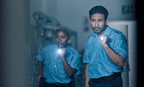 Security, surveillance and team of police investigation of crime in store at night using torch or flashlight for protection. Teamwork, emergency and professional safety employees search for criminal