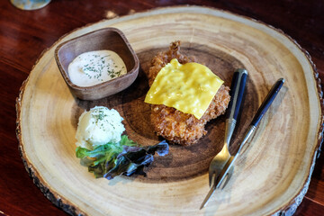 Chicken steak fried with slice cheese sald on wood dish