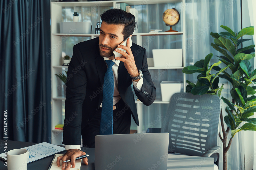 Poster diligent businessman busy talking on the phone call with clients while working with laptop in his of