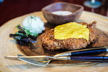 Chicken steak fried with slice cheese sald on wood dish