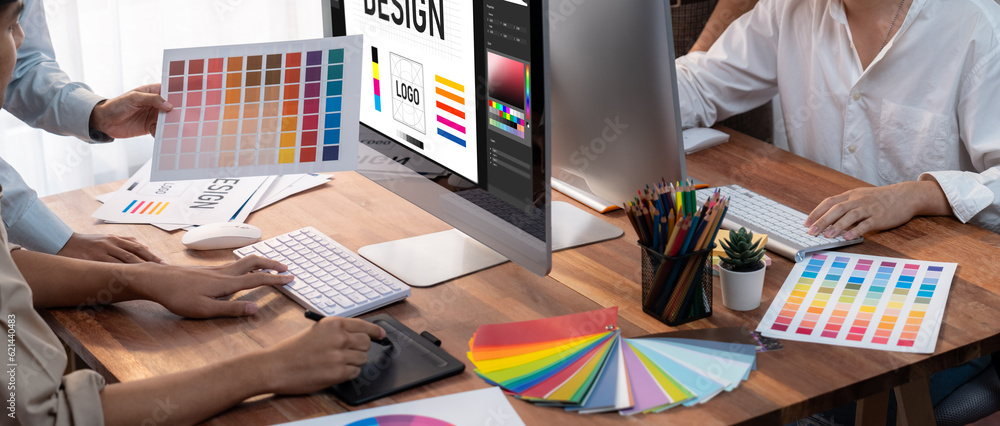 Poster Graphic designer work on computer laptop and with graphic drawing pen while brainstorming unique design with professional graphic team in modern digital studio workplace. Panorama shot. Scrutinize