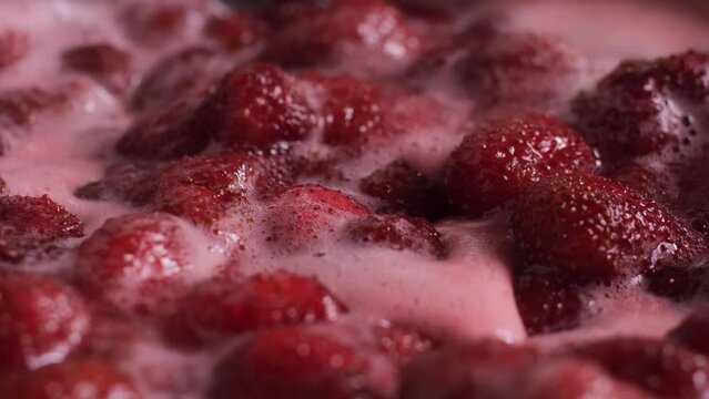 Pink foam for strawberry jam. Strawberries are boiled in a pot with sugar. The most delicious homemade strawberry jam. Soft selective focus on foam. An abstractly shaped picture with a partially shape