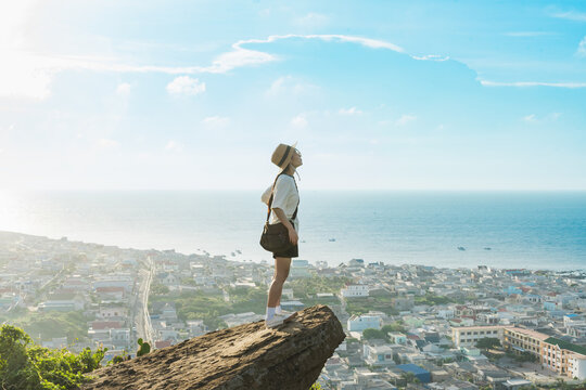 image of a girl srtanding  on a mountain looking down at the sea