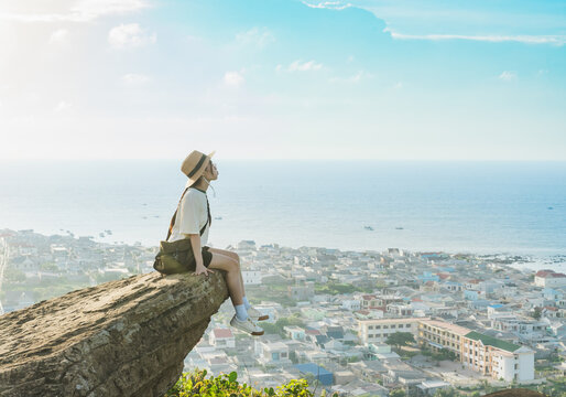 image of a girl sitting on a mountain looking down at the sea