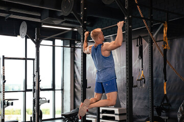 Fit and muscular man shakes his back on the simulator. Back view.