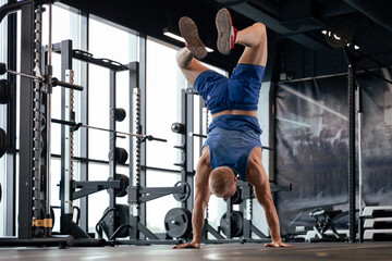 Strong man walking on hand during crossfit training in fitness club.