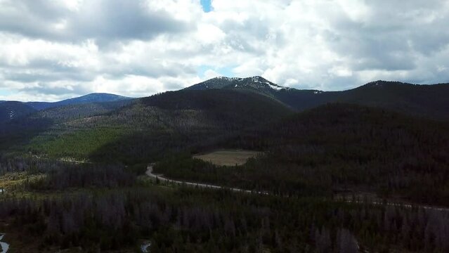 Aerial Panning Shot Of Road Amidst Trees Near Mountains Against Sky, Drone Flying Over Natural Landscape - Billings, Montana