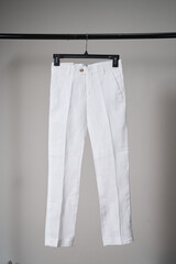White classic pants on hanger mockup. School uniform, branding mock up. Studio shot, close up, grey background            - 621453018