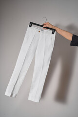White classic pants on hanger mockup. School uniform, branding mock up. Studio shot, close up, grey background            - 621453200