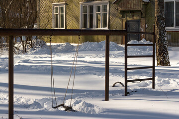 Children's playground with swings covered with snow in winter