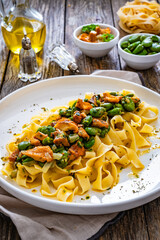 Tagliatelle with broad bean and chanterelle mushrooms on wooden table
