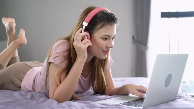 
Beautiful woman using laptop computer shopping online, social media and fashion trend at home. Teenage girl lying on bed and happy with conference online in internet at home.