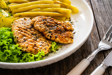 Grilled chicken breasts with yellow beans and boiled potatoes on wooden table
