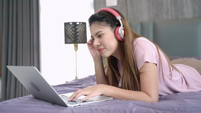 
Beautiful woman using laptop computer shopping online, social media and fashion trend at home. Teenage girl lying on bed and happy with conference online in internet at home.