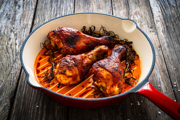 Pan fried chicken drumsticks on wooden background