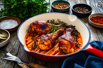 Pan fried chicken drumsticks on wooden background