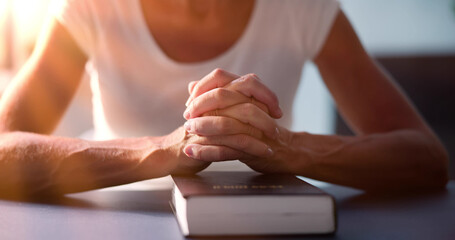 Obraz na płótnie Canvas Sunlight Falling On Woman's Hand Over Holy Bible