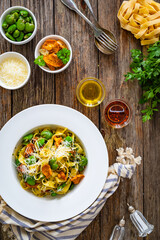 Tagliatelle with broad bean, chanterelle mushrooms and parmesan cheese on wooden table
