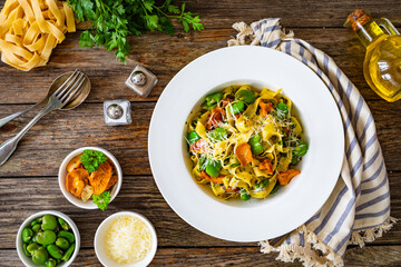 Tagliatelle with broad bean, chanterelle mushrooms and parmesan cheese on wooden table
