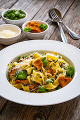 Tagliatelle with broad bean, chanterelle mushrooms and parmesan cheese on wooden table
