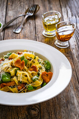 Tagliatelle with broad bean, chanterelle mushrooms and parmesan cheese on wooden table

