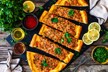 Top-down shoot of Turkish pide - slices of Turkish flatbread pizza with minced meat on wooden...