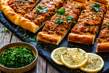Turkish pide - slices of Turkish flatbread pizza with minced meat on wooden background

