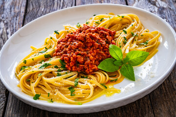 Linguine with minced pork meat in tomato sauce  with parmesan cheese and basil leaves served on wooden table
