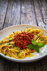 Linguine with minced pork meat in tomato sauce  with parmesan cheese and basil leaves served on wooden table
