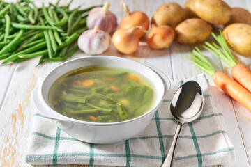 vegetable soup in a ceramic bowl and ingredients on wooden  table .