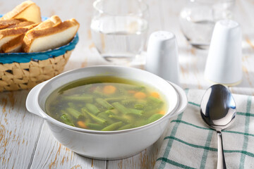 Bean soup in white bowl and spoon on wooden table.