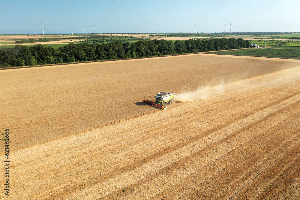 Poster combine harvester in action on wheat field. drone shoot!