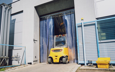 Forklift loader near big industrial storage warehouse.