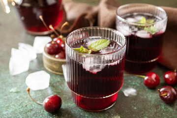 Cold refreshing cherry cola in a glass with ice on a stone background, summer juice.