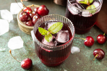 Cold refreshing cherry cola in a glass with ice on a stone background, summer juice.