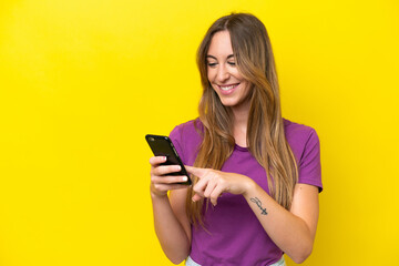 Naklejka premium Young caucasian woman isolated on yellow background sending a message or email with the mobile