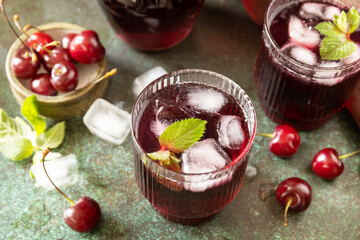 Cold refreshing cherry cola in a glass with ice on a stone background, summer juice.